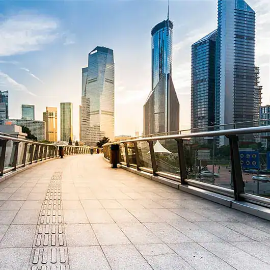 A modern cityscape with tall glass skyscrapers at sunrise, viewed from an empty, wide pedestrian walkway—showcasing the vibrant energy of a city powered by a pre-eminent electrical service in Alamance County, NC.